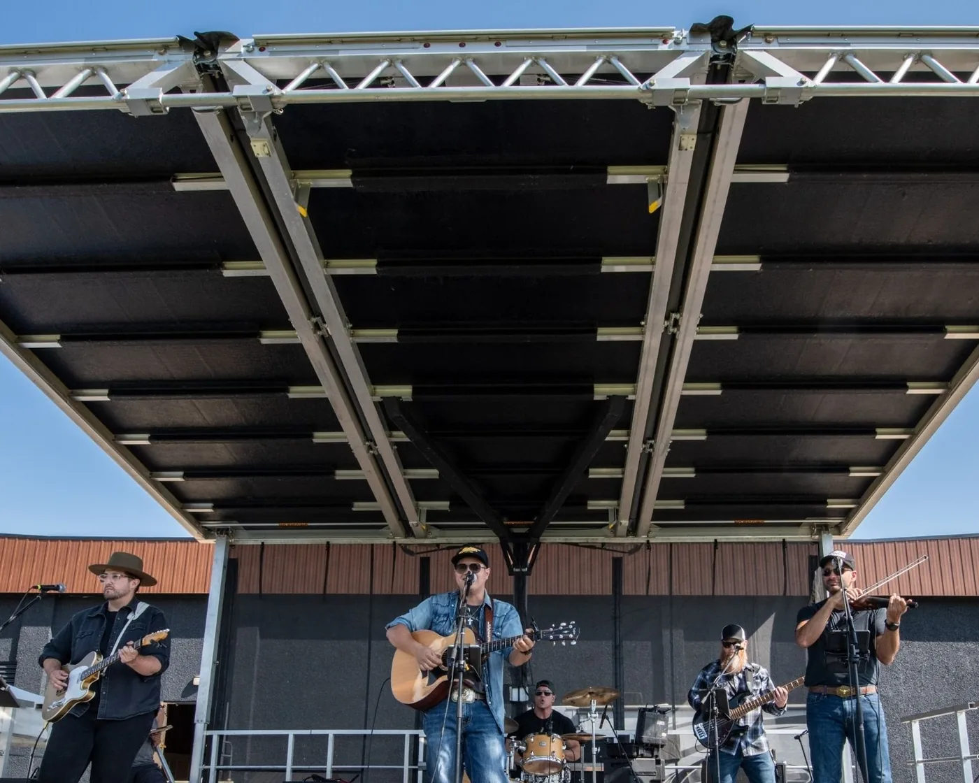A band performing together beneath the outdoor canopy in 2025