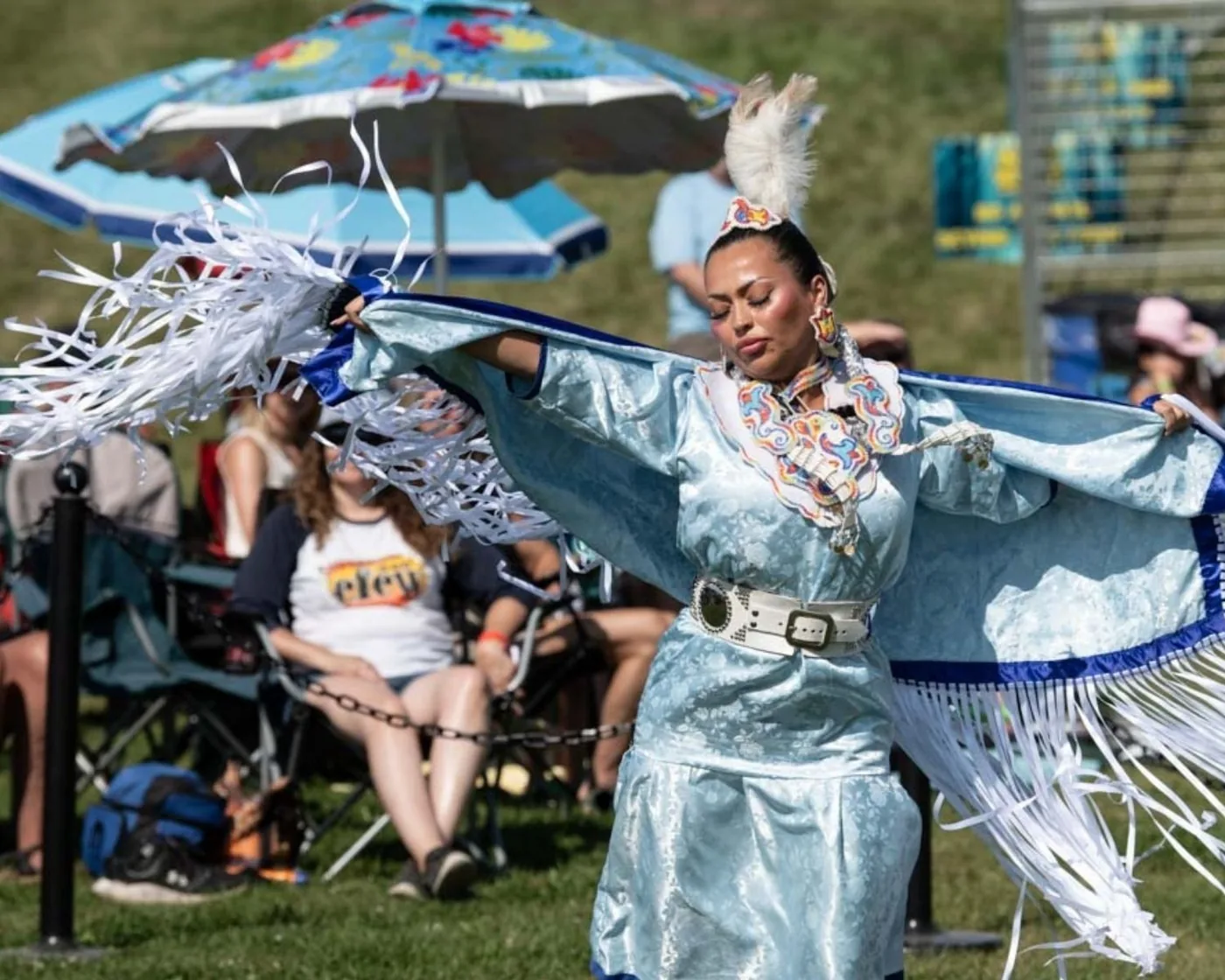 A dancer in regalia moving across the festival grounds in 2025